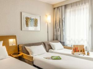 a hotel room with two beds and a couch at Novotel Lille Centre Gares in Lille +150 photos