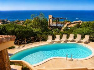 a swimming pool with chairs and the ocean in the background at Villa Turchese - Key to Villas in Costa Paradiso