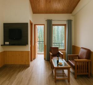 a living room with a couch and a table and a television at Chaman Vatika in Kasol