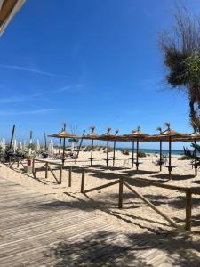 a beach with a bunch of straw umbrellas on the sand at Villa guiris in Barbate