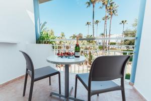 a table and chairs on a balcony with a bottle of wine at Sagitario Princesa Playa in Son Xoriguer