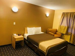 a hotel room with a bed and a chair at M Star Hotel Mansfield in Mansfield