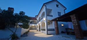 a large white building with a courtyard at night at Apartmani Lucija 3 in Zubovići