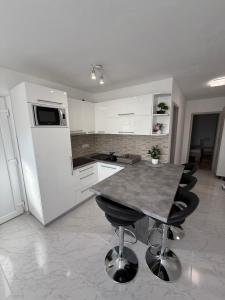a kitchen with white cabinets and a table with black stools at Apartmani Lucija 3 in Zubovići