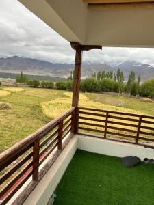a balcony with a view of a field and mountains at Cho Farm House in Leh