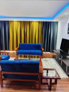 a living room with blue couches and a yellow curtain at SixPoint Victoria in Kisumu