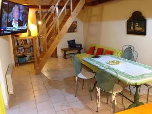 a living room with a table and chairs and a tv at La Fée Du Val - Gite En Ardèche in Rosières