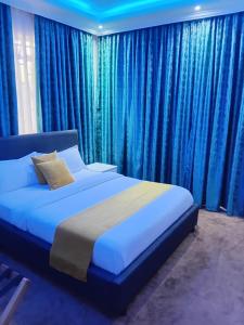 a bedroom with a large bed with blue curtains at SixPoint Victoria in Kisumu +30 photos