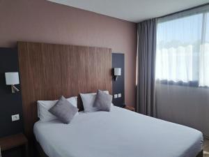 ein Schlafzimmer mit einem großen weißen Bett und einem Fenster in der Unterkunft The Originals City, Hôtel Le Sextant, Toulouse Sud in Labège + 11 Fotos