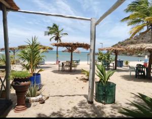 a beach with tables and palm trees and the ocean at Apartamento en puerta del sol 17 in La Loma