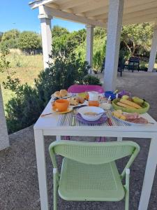 ein weißer Tisch mit Essen darauf und zwei Stühlen in der Unterkunft Alma Bed & Breakfast 15 minuti da Bosa e comodo parcheggio in Sennariolo