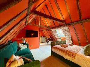 a bedroom with an orange ceiling with a bed and a couch at The Great House Lavenham Hotel & Restaurant in Lavenham