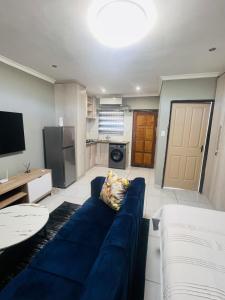 a living room with a blue couch and a kitchen at Luxury Executive Apartment in Vanderbijlpark