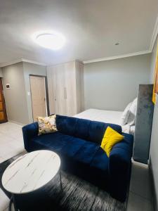 a living room with a blue couch and a bed at Luxury Executive Apartment in Vanderbijlpark