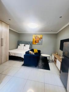 a bedroom with a bed and a blue couch at Luxury Executive Apartment in Vanderbijlpark