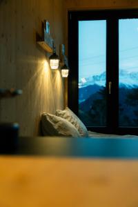 a room with a bed and a window with a view at Unbound Hütte Lenzerheide in Tiefencastel