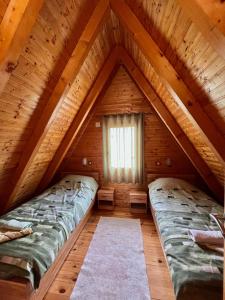 two beds in a log cabin with a window at Vikendica Anja in Žabljak