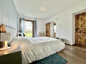 a white bedroom with a large bed and a window at La Bergerie de Losse in Traize