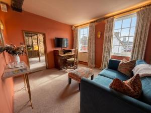 a living room with orange walls and a blue couch at The Great House Lavenham Hotel & Restaurant in Lavenham
