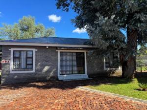 a brick house with a tree and a brick driveway at CE Guesthouse in Vanderbijlpark