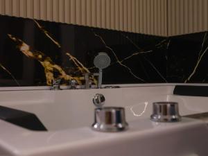 a bathroom sink with a black and gold marble wall at Rentalica in Belgrade