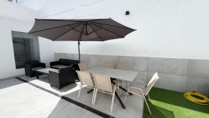 a table and chairs with an umbrella in a room at The white house in Vecindario