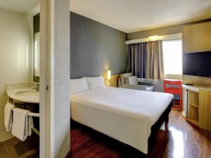 a hotel room with a large white bed and a desk at ibis Tambore in Barueri +91 photos