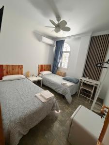 a bedroom with two beds and a ceiling fan at La casa de Lola in Caleta De Velez