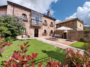 a large stone building with an umbrella in a yard at Casa Dulcinea en Brañosera Montaña Palentina. in Brañosera