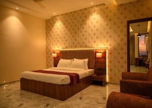 a bedroom with a bed and a mirror and a chair at Hotel ShyamLeela - Khatushyamji in Khātu +63 photos