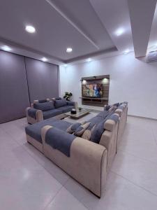 a living room with four large couches and a tv at aqua chalets شاليهات أكوا in Al Rama