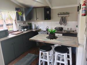 a kitchen with a wooden table and two stools at Log in At 118 Loghome in Meyerton
