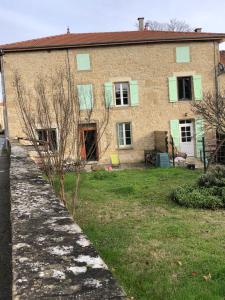 a brick house with green shuttered windows and a yard at Gîte des collines in Saint-Donat-sur-lʼHerbasse