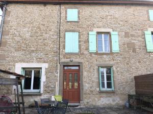 a brick building with a red door and a table at Gîte des collines in Saint-Donat-sur-lʼHerbasse