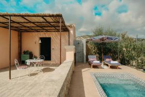 a patio with a table and chairs and a pool at Braccialieri Luxury Resort in Avola