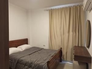 a bedroom with a bed and a desk and curtains at High quality apartment Madinty in Cairo