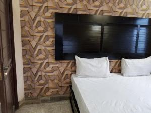 a bedroom with a bed with a wooden wall at Fivee Hotel Model Town Multan in Multan
