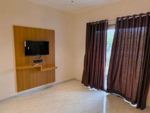 a room with a tv and a window with curtains at Berry Fresh Stays Mahabaleshwar With Pool in Mahabaleshwar