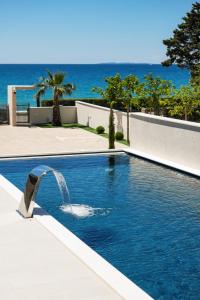 a pool with a water fountain in front of the ocean at Bumblebee apartments & rooms with pool in Novalja