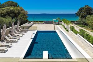 a swimming pool with chairs and the ocean in the background at Bumblebee apartments & rooms with pool in Novalja +75 photos