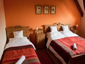 two beds in a room with orange walls at St.Michael Panzió Lovaspark in Vasszentmihály