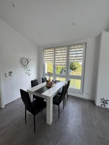 a dining room with a white table and black chairs at Bungalow Lange in Schwielochsee