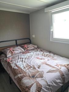 an unmade bed in a bedroom with a window at Camping de Zandhorst, Chalet Madera in Wouterswoude