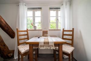 a dining room table with two chairs and two windows at Bolter Mühle - DZ Hanfbuchte in Rechlin