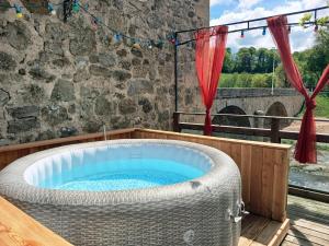 a hot tub on a deck with a stone wall at La Belle Tençoise in Tence
