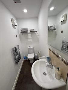 a white bathroom with a sink and a toilet at Ballycastle, Beachside Apartment in Ballycastle +22 photos