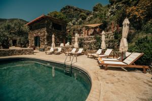 a pool with chairs and umbrellas next to a building at Ellafos Traditional Living-Elafonisi Couples Retreat in Elafonisi