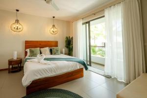 a bedroom with a bed and a large window at Chic poolside haven 3BR steps from the beach in Cap Malheureux +62 photos