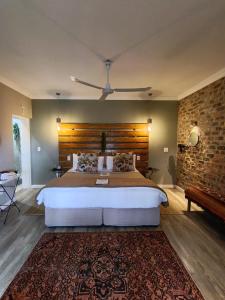 a bedroom with a large bed and a brick wall at Earthbound Guest House in Oudtshoorn +183 photos