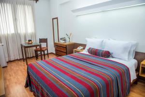 a bedroom with a large bed with a colorful striped blanket at San Agustin Riviera in Lima